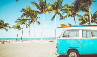 photo-wallpaper-turquoise-camper-van-with-surfboard-on-a-palm-lined-beach-in-retro-summer-light